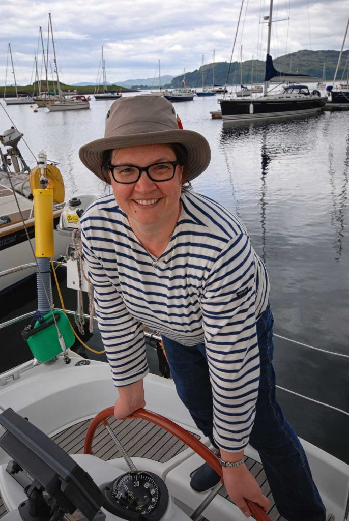 Anja behind the yacht steering wheel in Dunstaffnage Marina