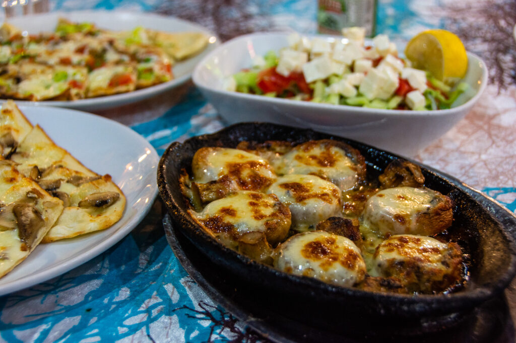 A cast iron dish of mushrooms filled with cheese, salad and vegetarian pide in Fethiye