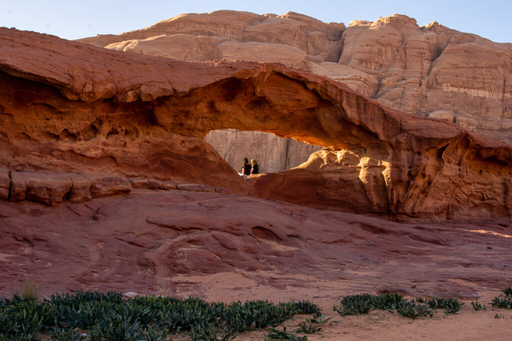 two people sitting in a rock arch in Wadi Rum, Jordan